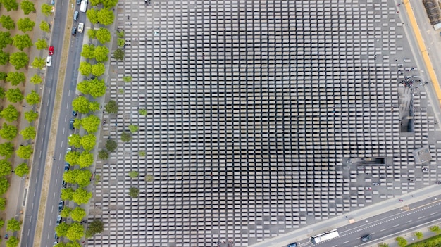 An aerial shot of a large parking lot with multiple electric vehicle charging stations available for public use, with a variety of electric vehicles parked and charging.