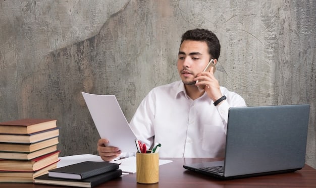 A person sitting at a desk, looking concerned while reviewing documents, with a laptop displaying a government benefits application website in the background. The scene conveys a sense of urgency and importance.